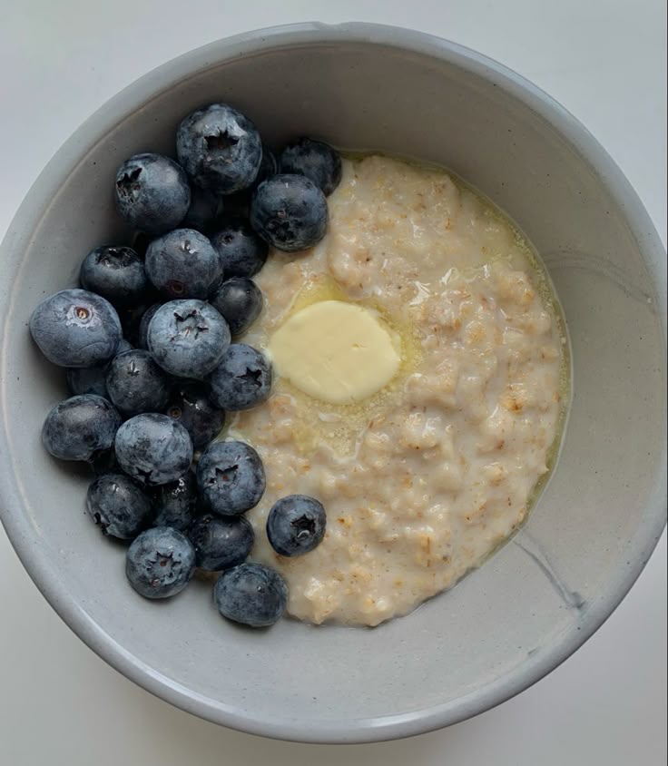 fotografija prikazuje činiju sa ovsenom kašom, maslacem i svežim borovnicama kao naslovnu fotografiju za blog tekst o tradicionalnoj ruskoj kaši, istoriji, dobrobiti za zdravlje i načinu tradicionalne pripreme