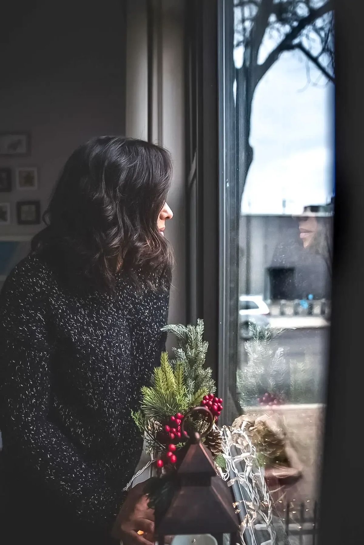 Fotografija koja prikazuje ženu za vreme praznika koja sedi sama i gleda kroz prozor kao simbol usamljenosti i praznične depresije o čemu govorim u blog tekstu