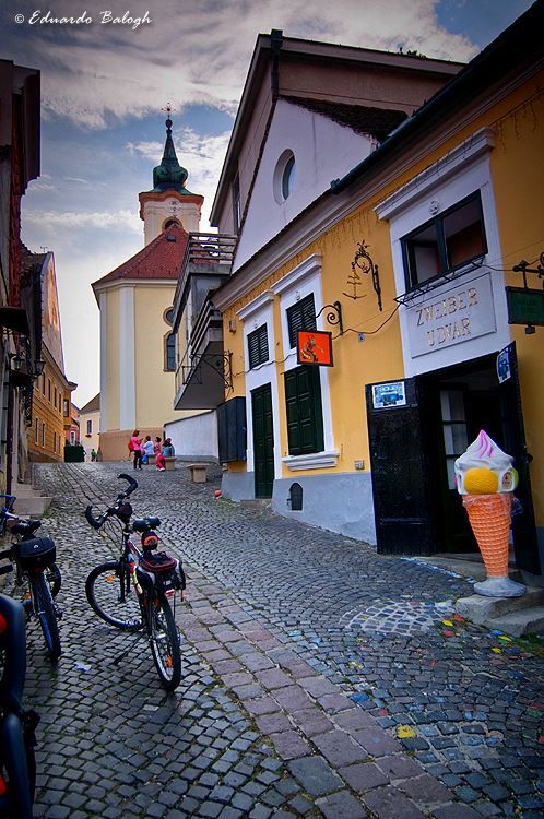 Ulica u Sent Andreji sa kaldrmom i crkvenim tornjem u pozadini